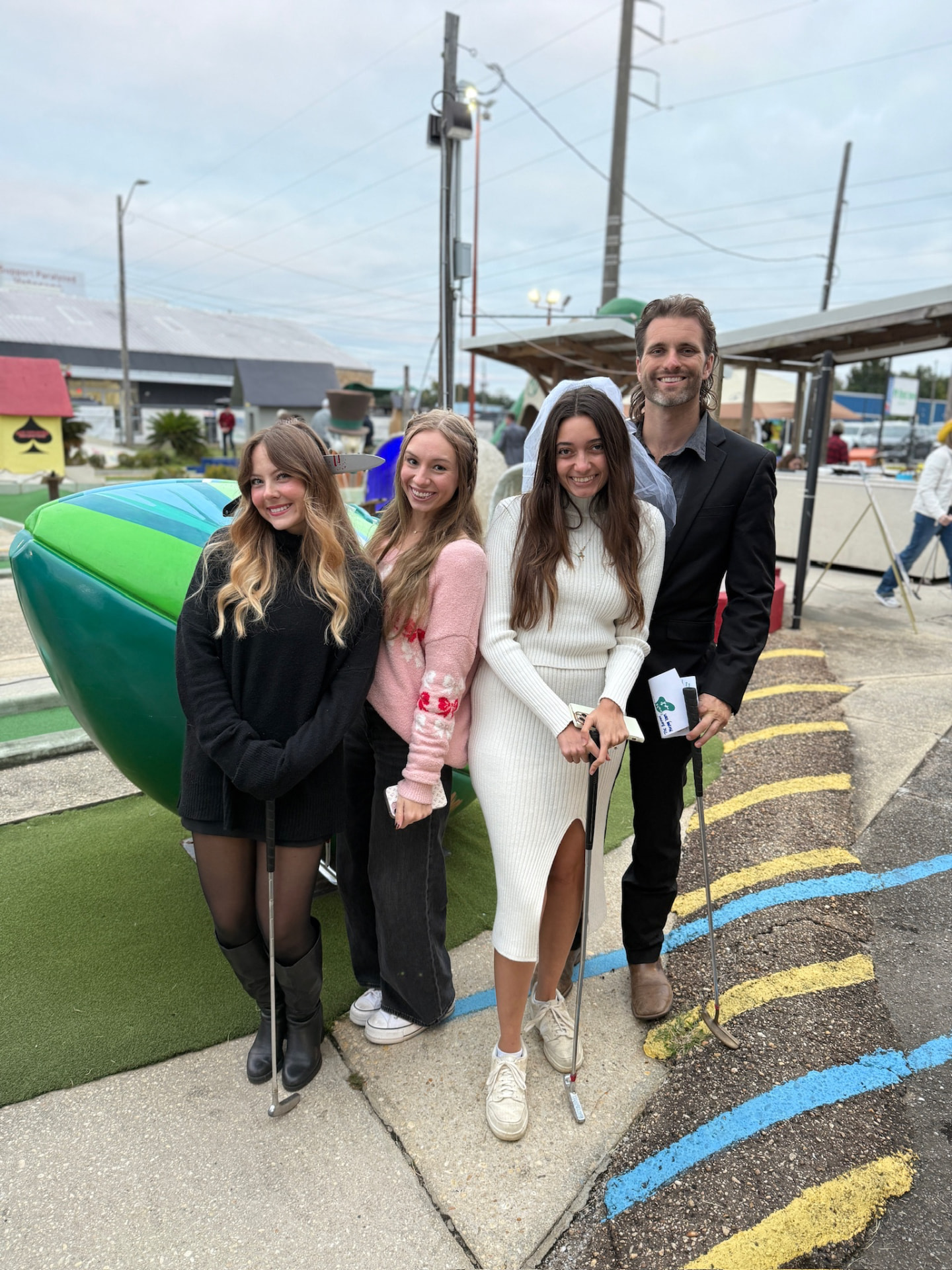 Four-player team with putters posing in front of a Goofy Golf landmark