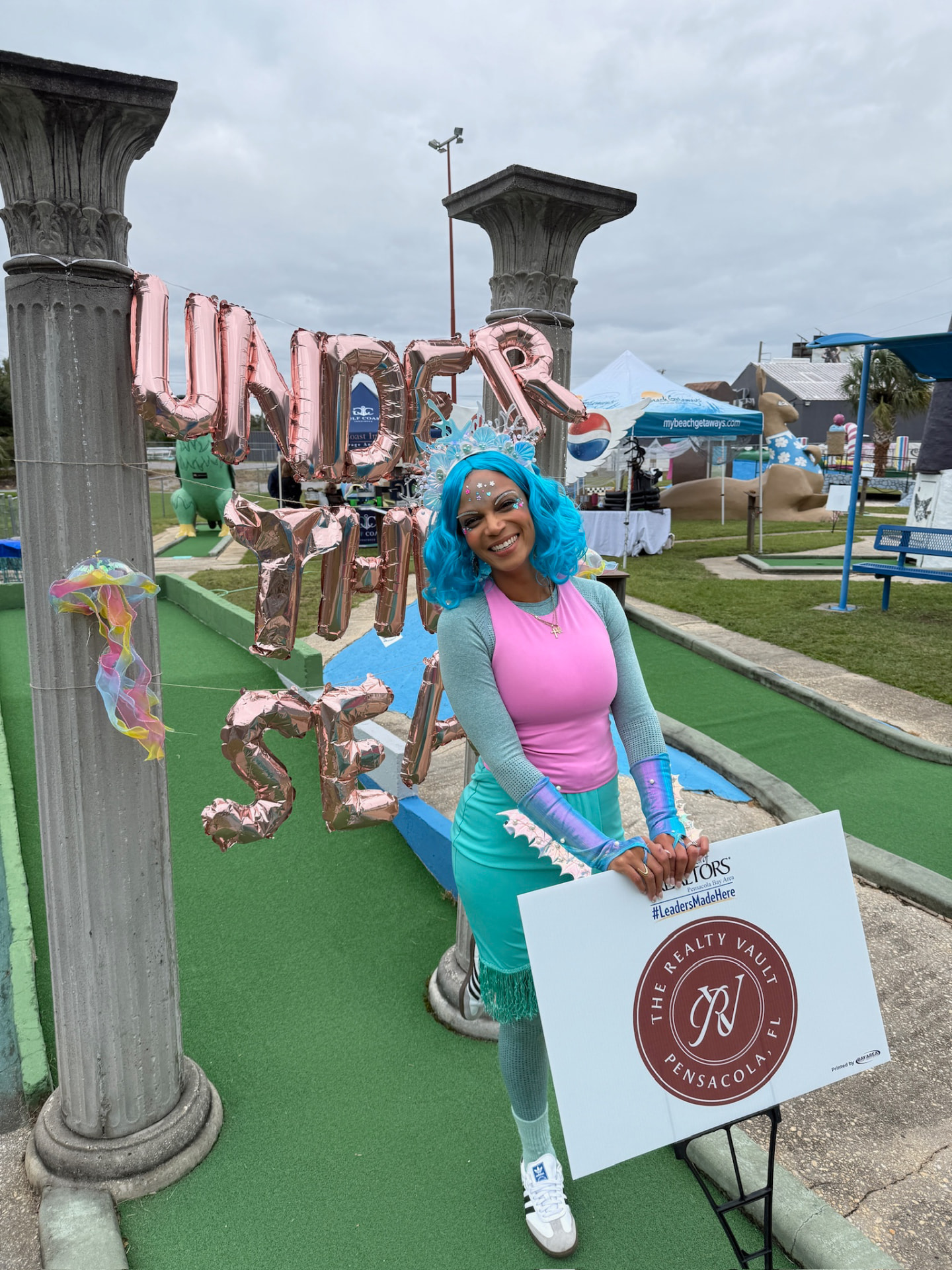 Costumed REALTOR® at the Under the Sea hole holding a sponsor sign