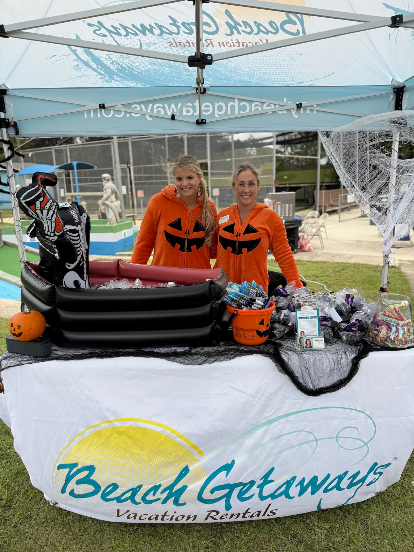Sponsors in pumpkin costumes at the Beach Getaways Vacation Rentals hole tent